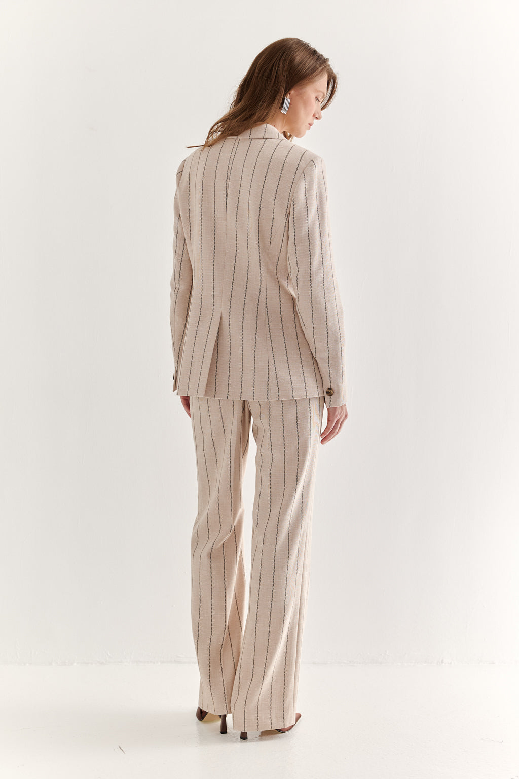 Woman wearing a beige pinstripe suit on a white background