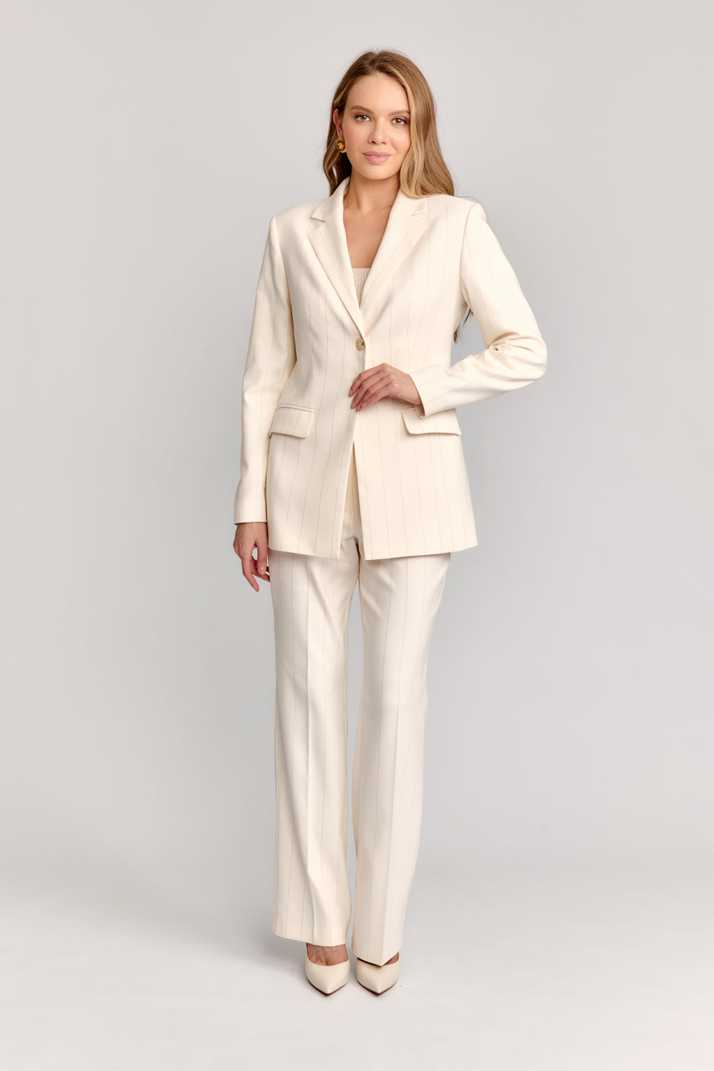 Woman wearing a cream suit on a light gray background