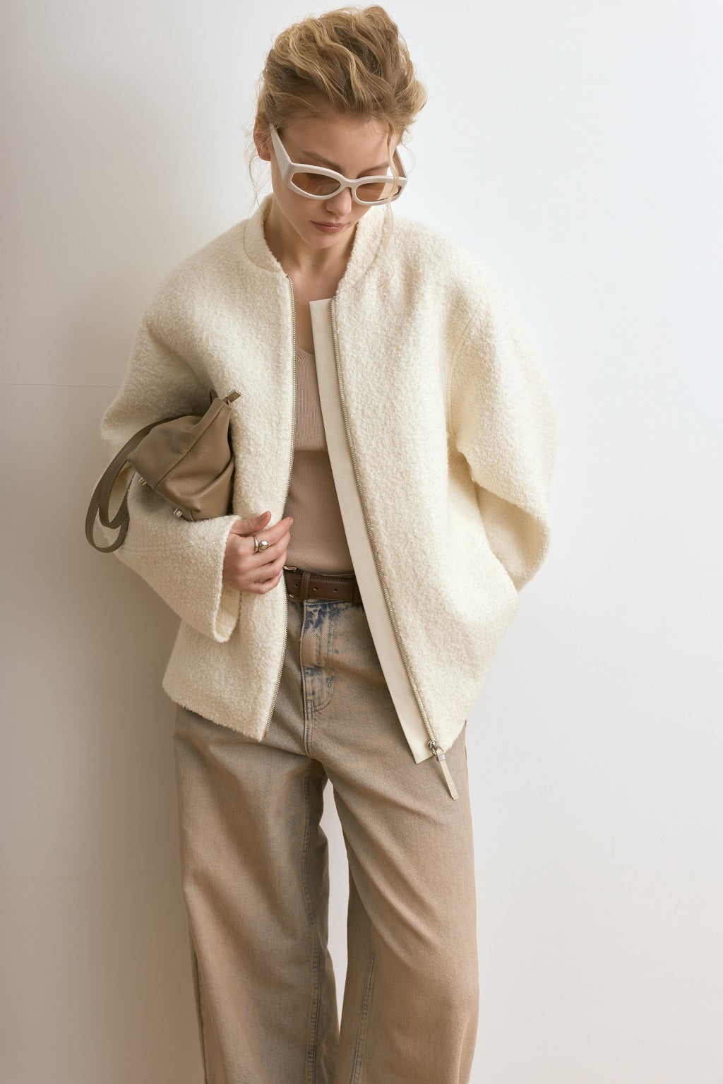 Person wearing a cream-colored coat and beige pants against a white background