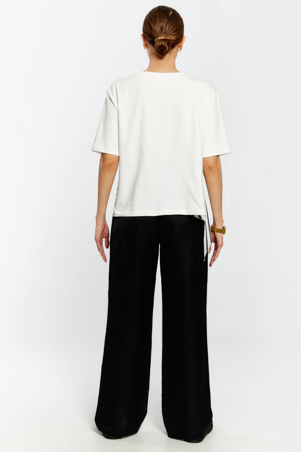 Person wearing a white t-shirt and black pants on a white background