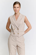 Woman wearing a beige plaid suit with a vest on a white background