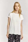 Woman wearing a white t-shirt and black pants with white patterns on a plain background