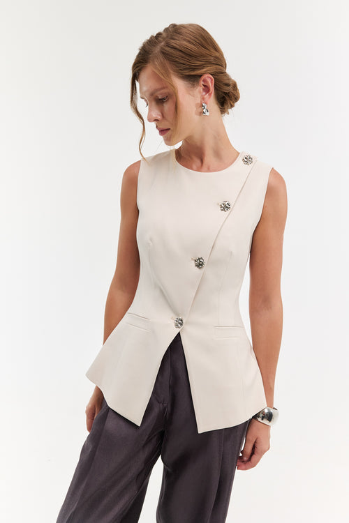 Woman wearing a white sleeveless blazer over dark pants on a white background