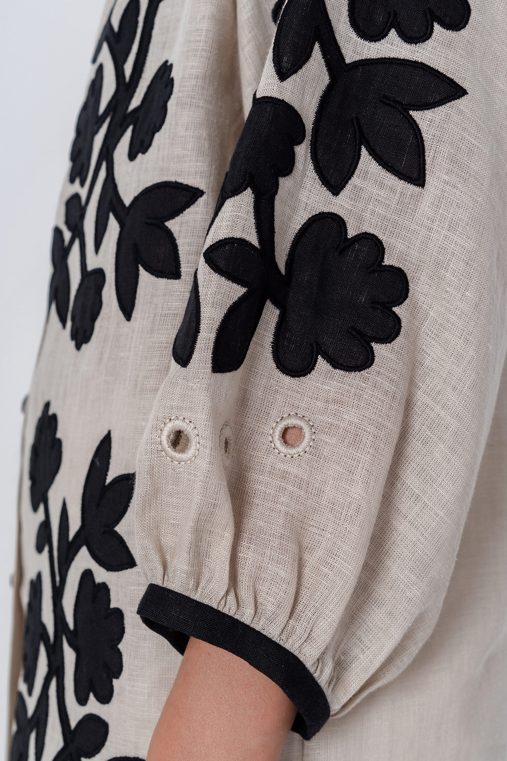 Close-up of a garment with black floral patterns on a beige background