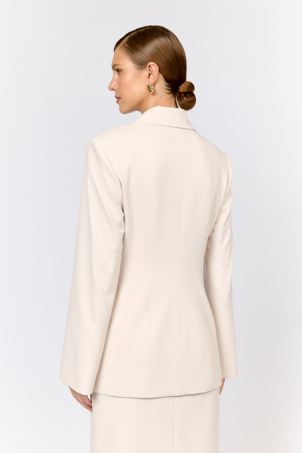 Woman wearing a beige suit on a light gray background