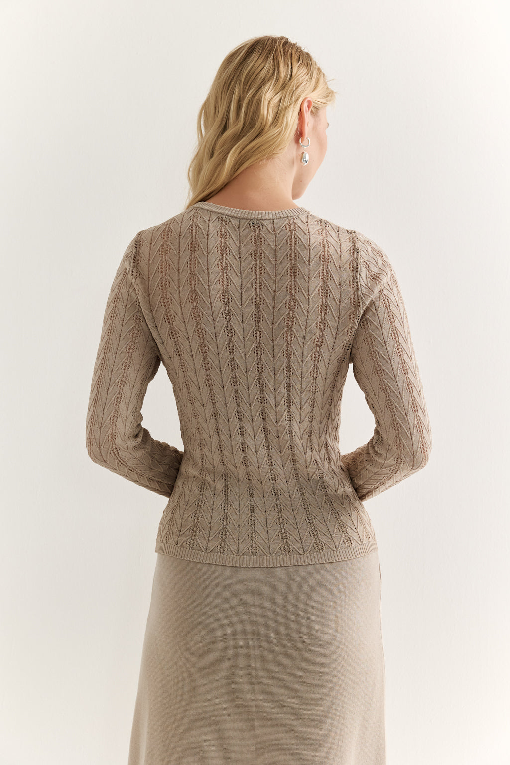 Woman wearing a beige knitted cardigan on a white background