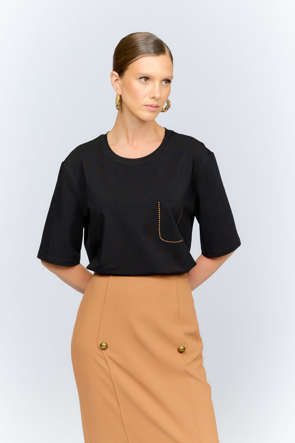 Woman wearing a black top and beige skirt on a white background