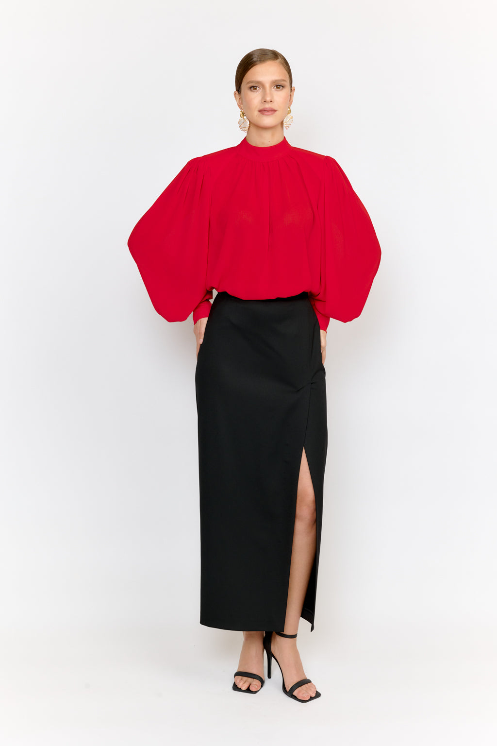 Woman wearing a red blouse and black skirt on a white background