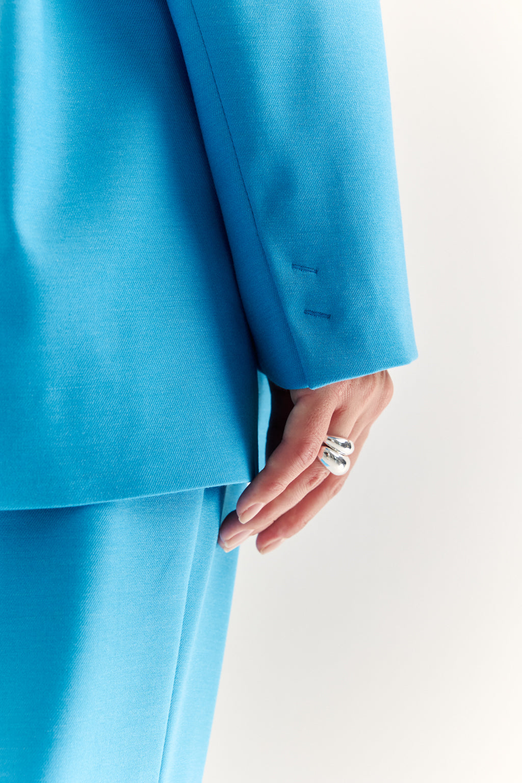 Close-up of a person wearing a bright blue suit with a white background