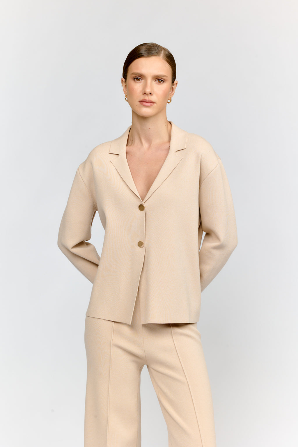 Woman wearing a beige suit on a light gray background