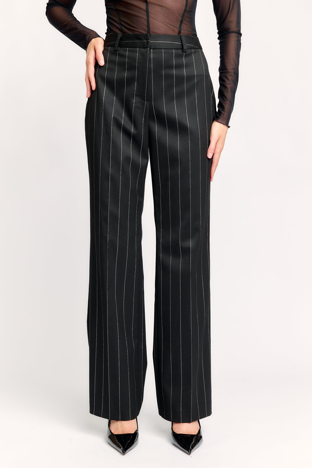 Black pinstripe pants worn by a person on a white background