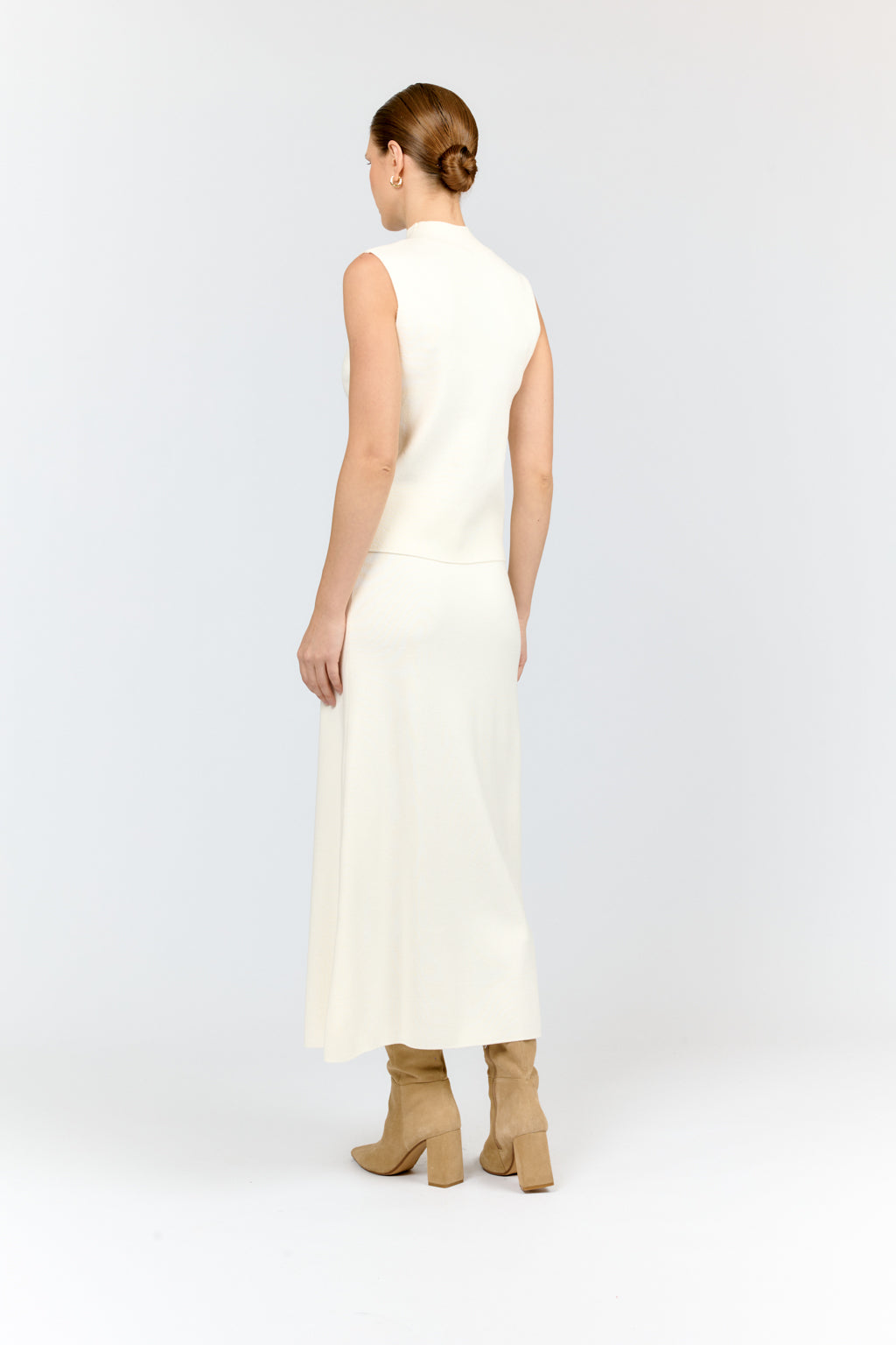 Woman wearing a white sleeveless dress on a plain background