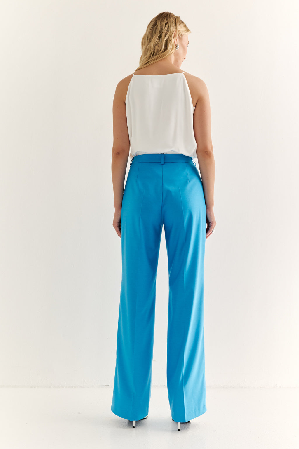 Woman wearing a white top and blue pants on a white background
