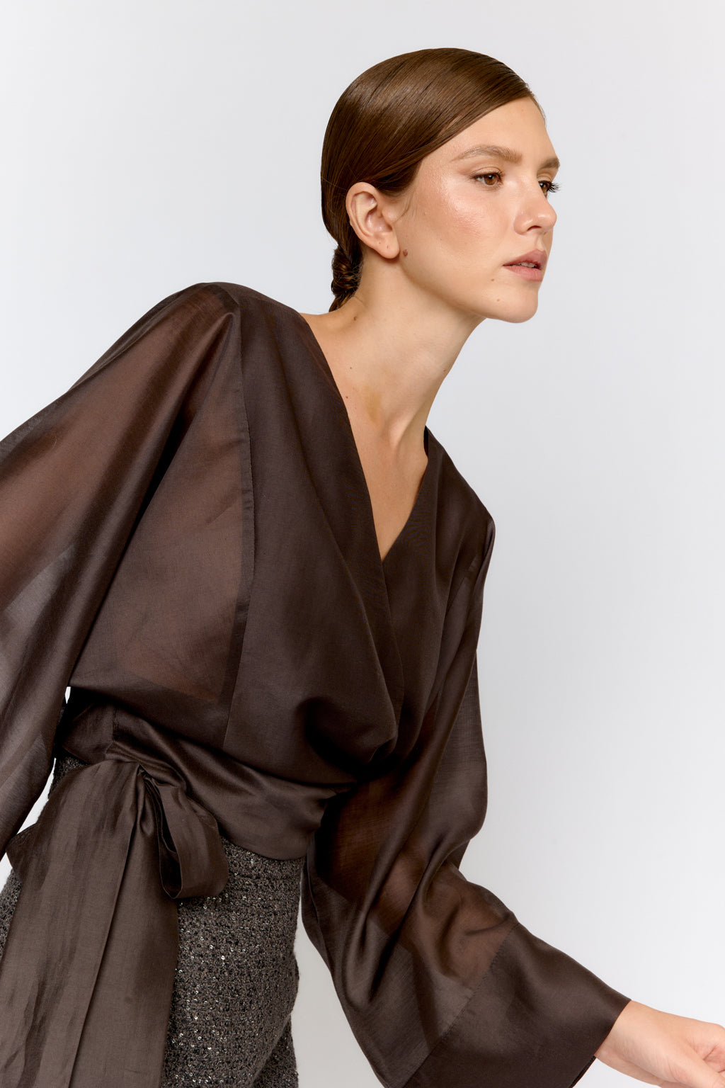 Woman wearing a brown draped garment against a white background