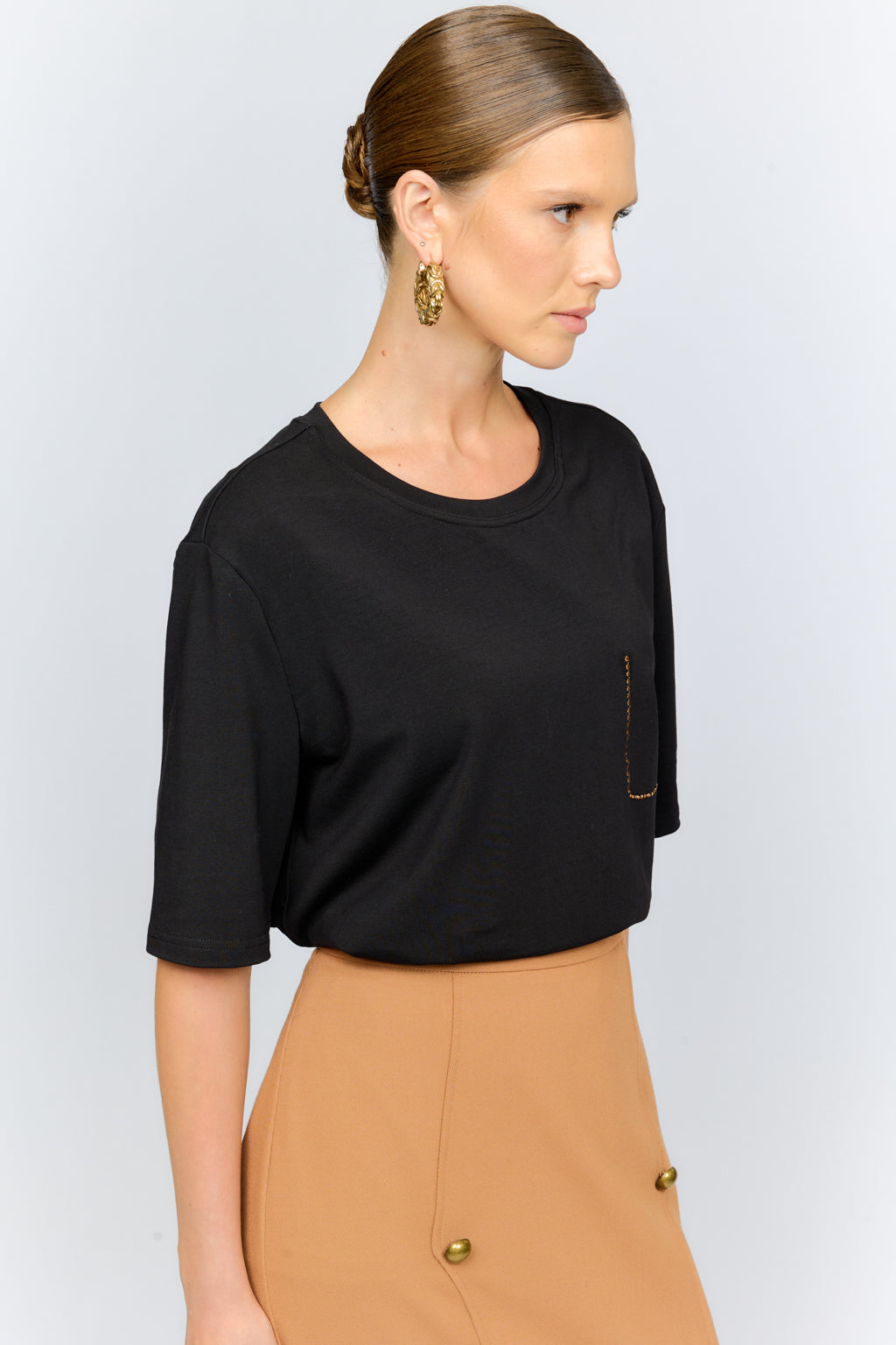 Woman wearing a black top and tan pants on a white background