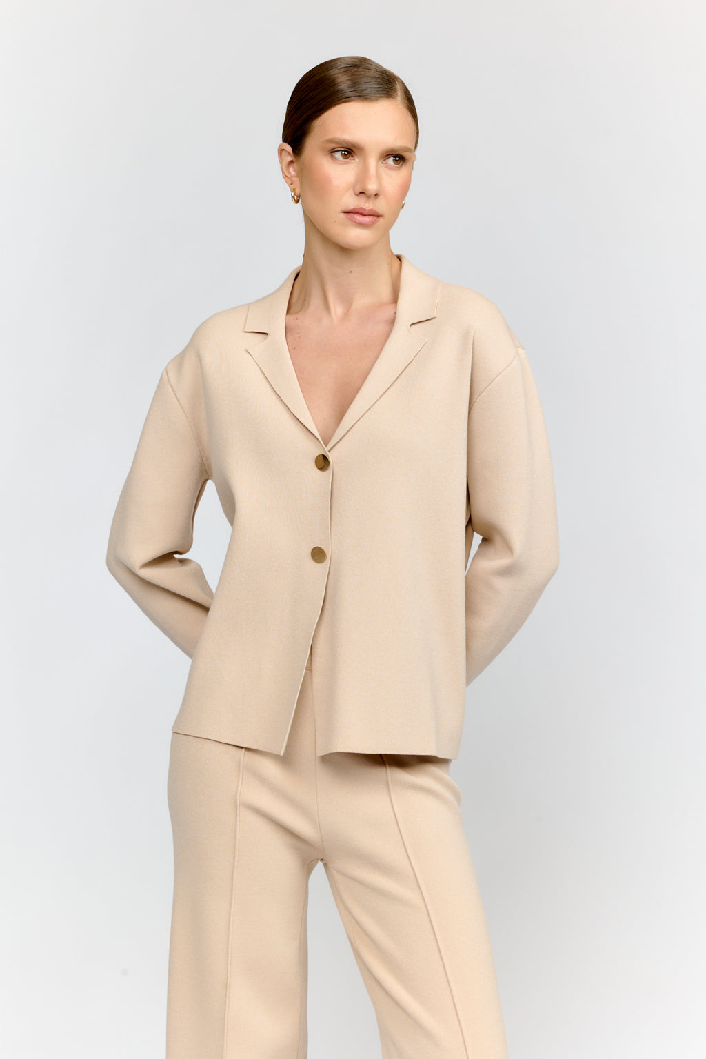 Woman wearing a beige suit on a light gray background