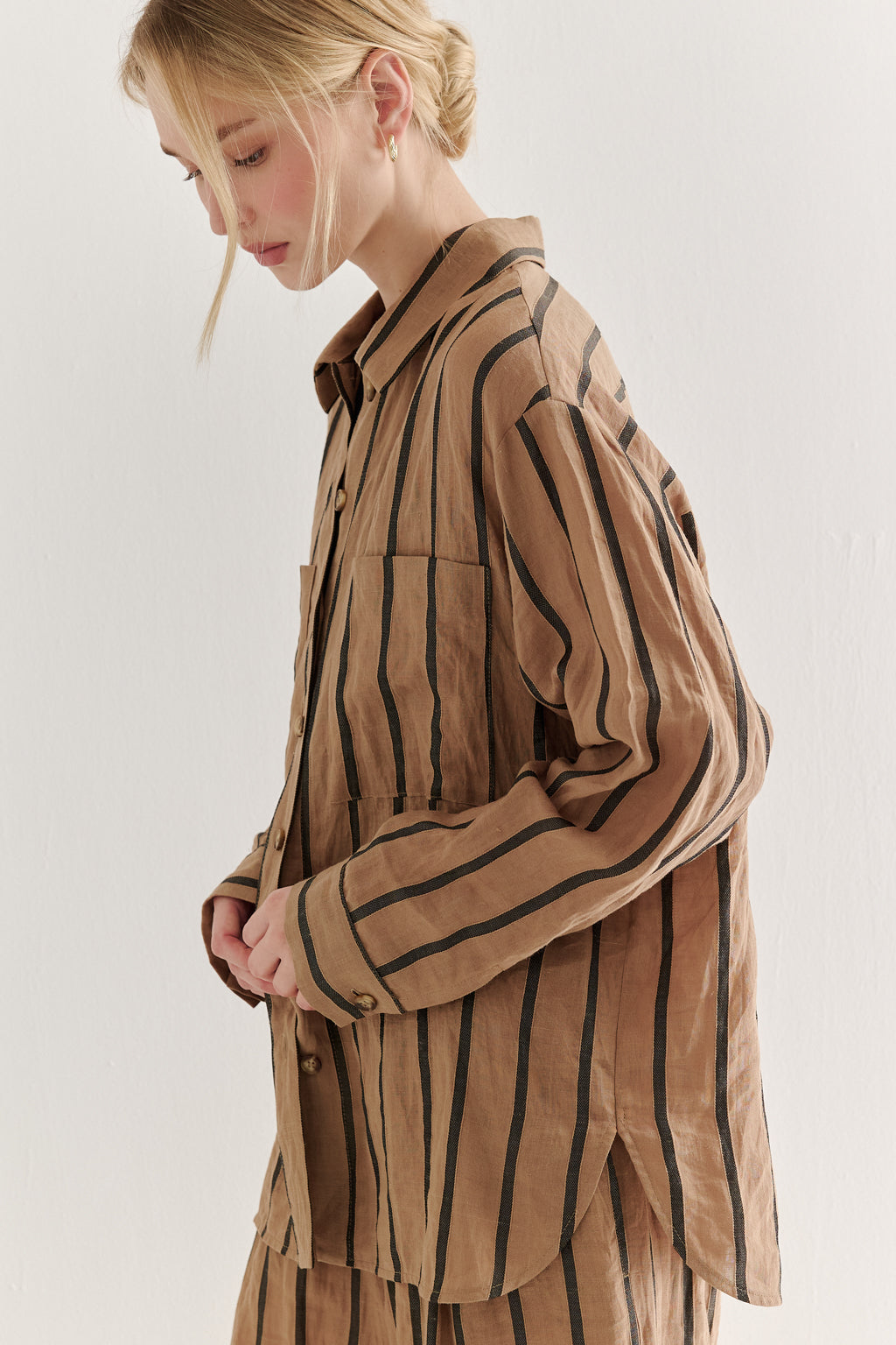 Woman wearing a brown striped shirt against a white background