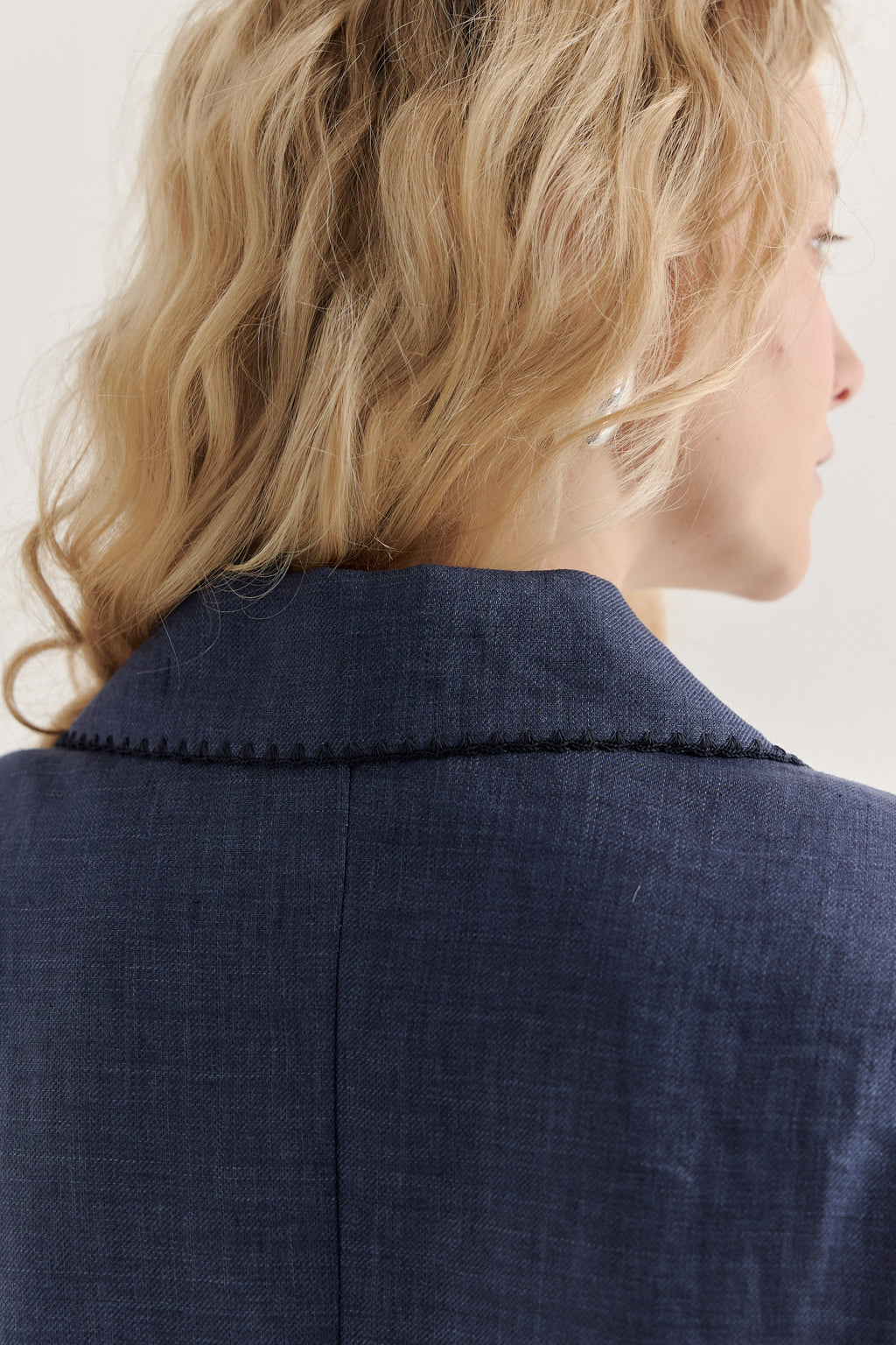 Close-up of a person wearing a navy blue coat with a white background