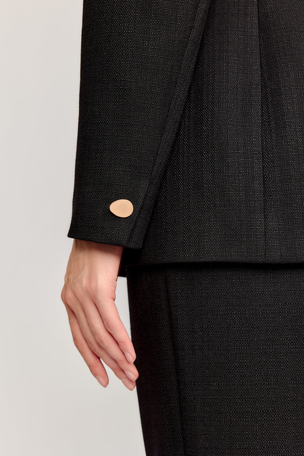 Close-up of a black suit jacket with a button on a light gray background