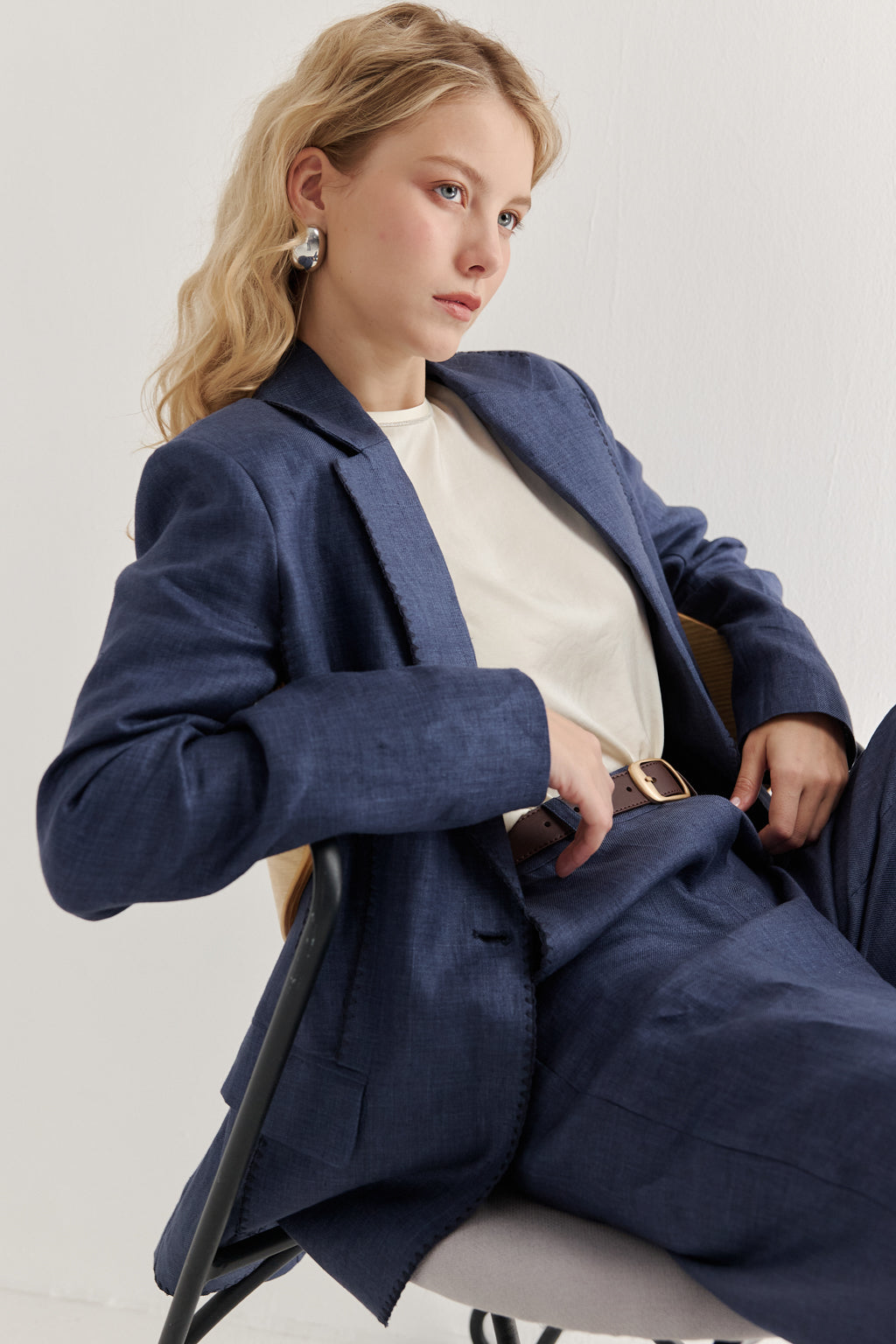 Woman wearing a navy blue suit sitting on a chair against a light background