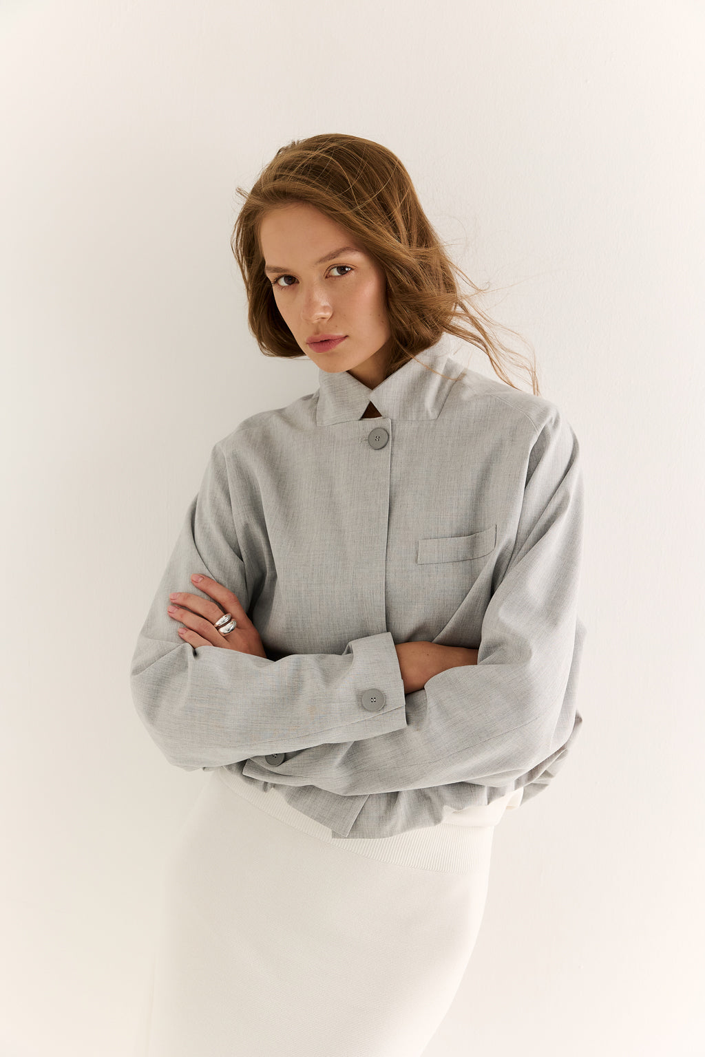 Woman wearing a light gray oversized shirt against a white background