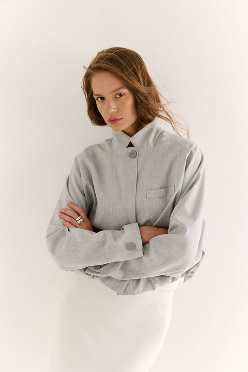 Woman wearing a light gray oversized shirt against a white background