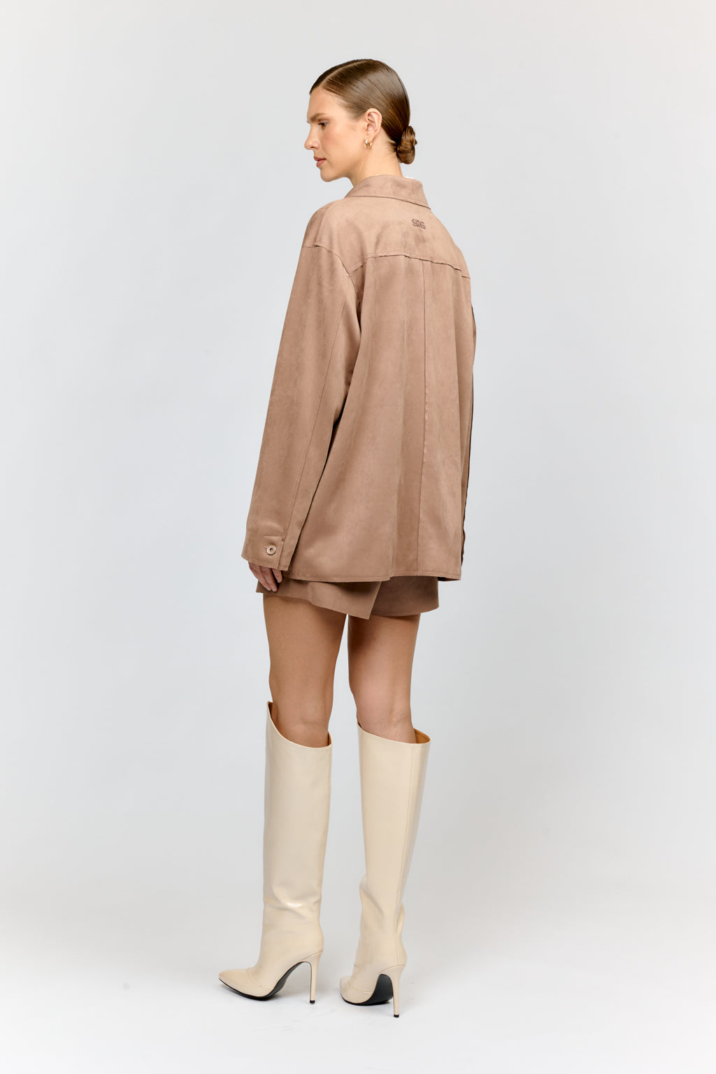 Woman wearing a beige coat and cream knee-high boots on a white background