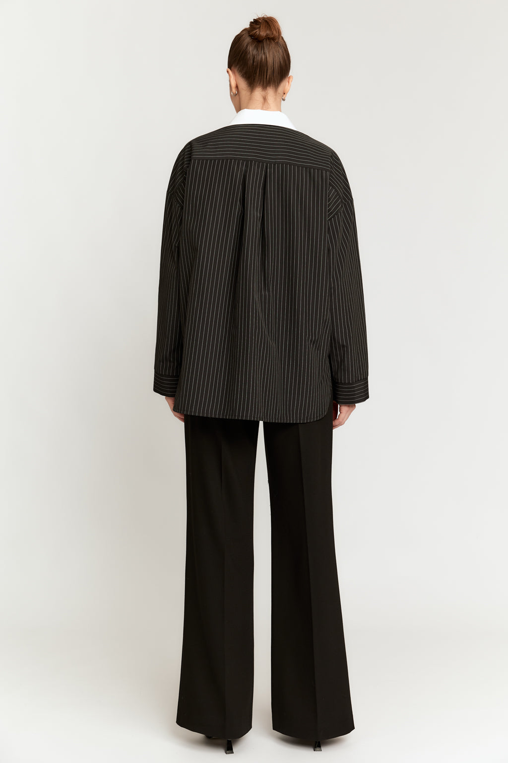 Person wearing a black pinstripe blazer and pants on a white background