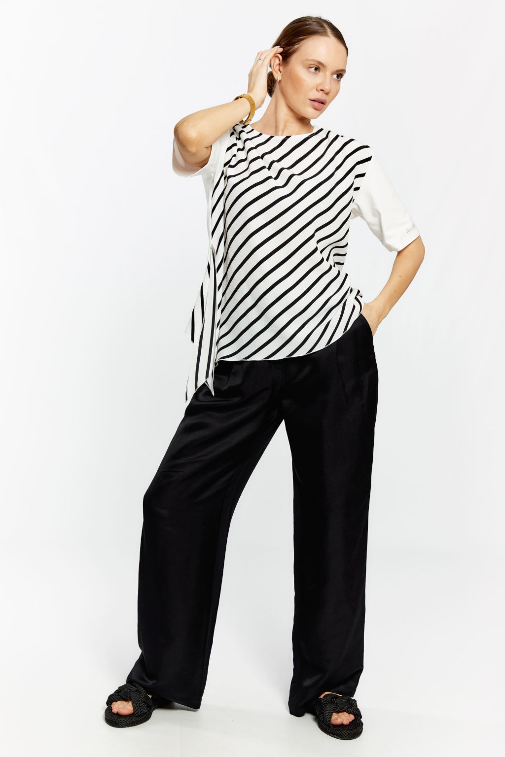 Woman wearing a black and white striped top and black pants on a white background