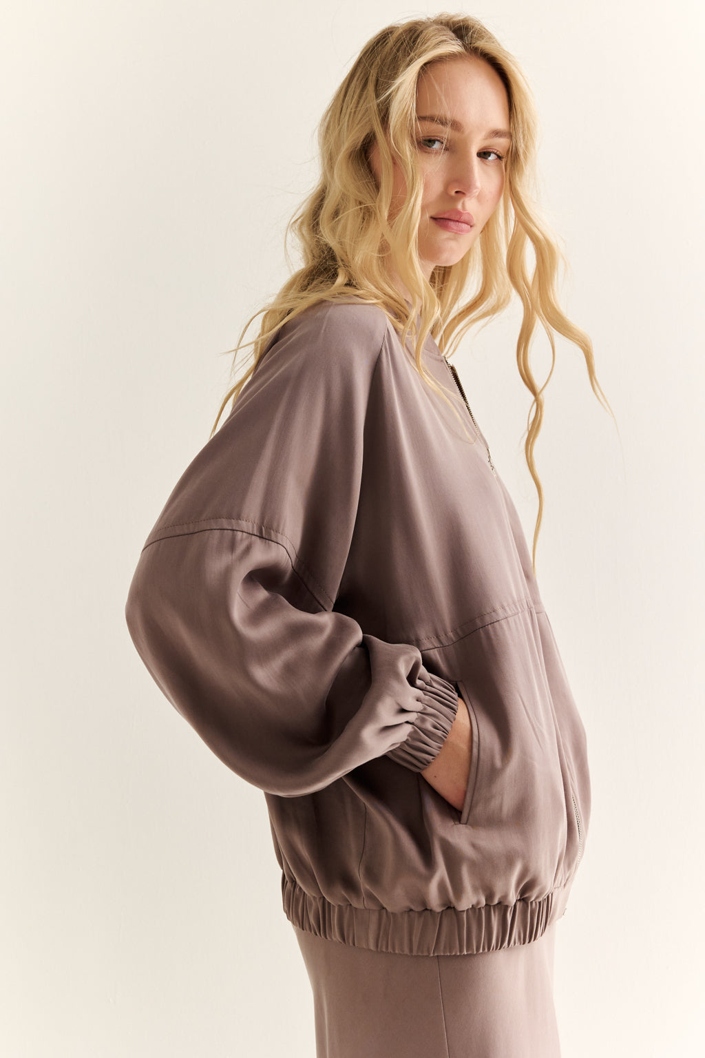 Woman wearing a brown oversized sweatshirt on a light background