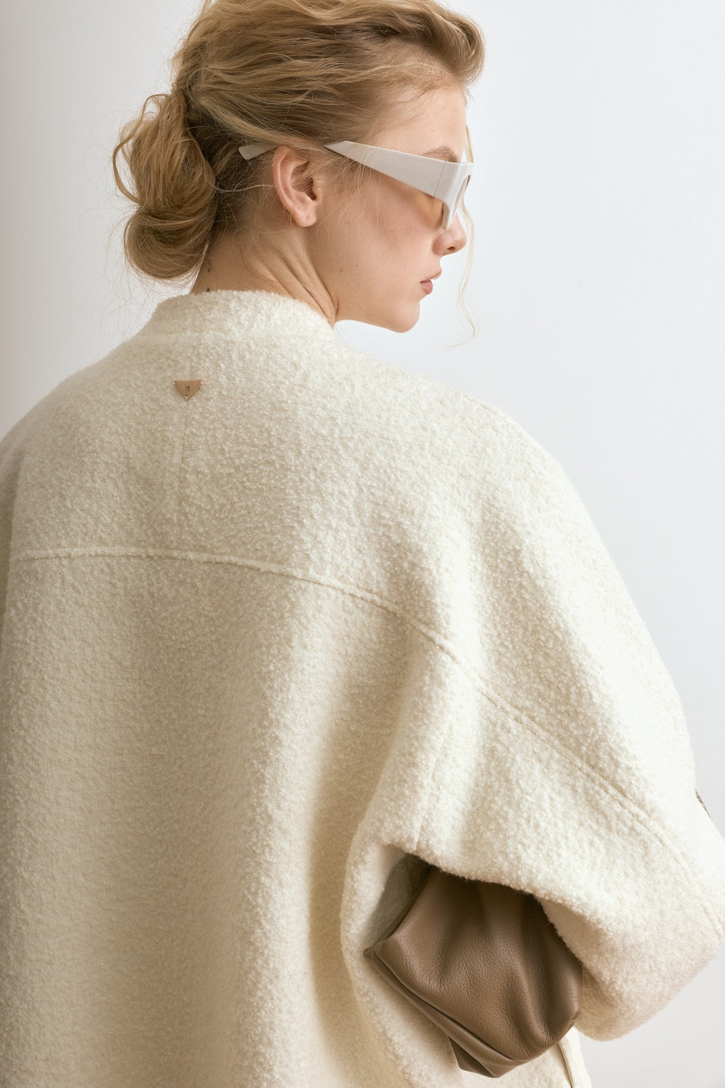 Person wearing a beige poncho against a plain background