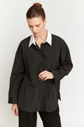 Woman wearing a black pinstripe shirt with a white collar on a white background