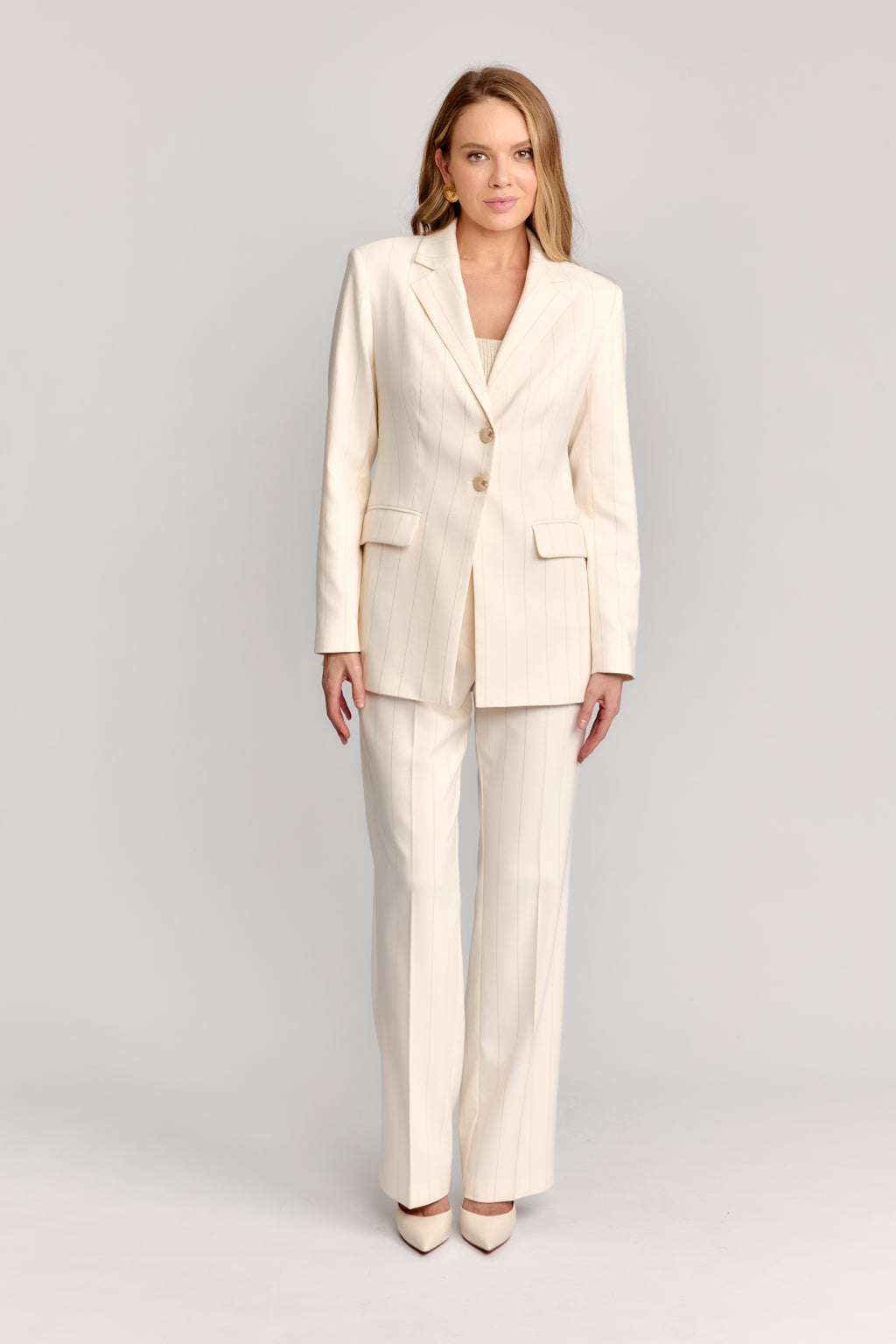 Woman wearing a cream-colored suit on a light gray background