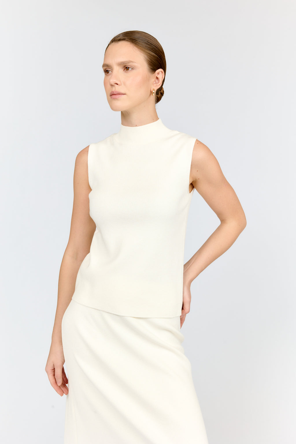 Woman wearing a white sleeveless dress against a light gray background