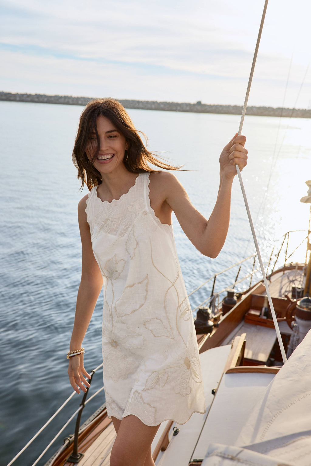 Woman in a white dress on a boat with water and sky in the background