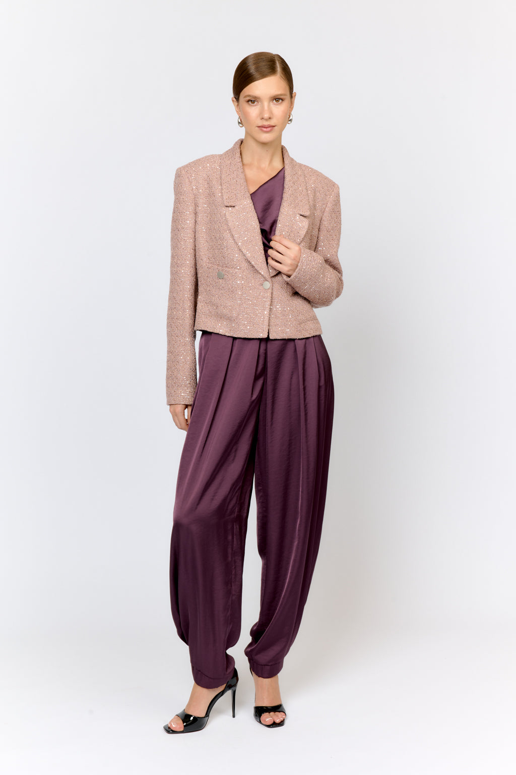 Woman wearing a beige blazer and purple pants on a white background
