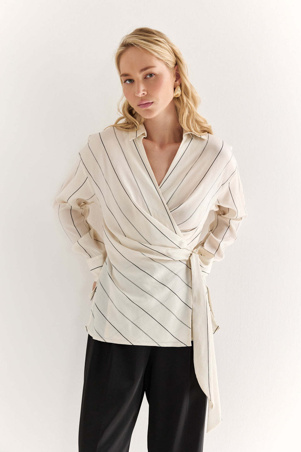 Woman wearing a beige and white striped shirt with a white background