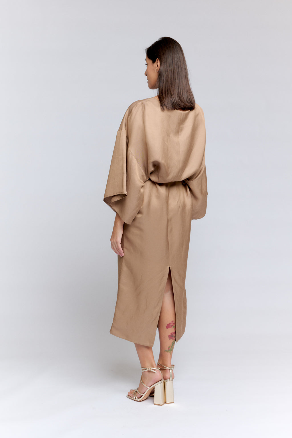 Woman wearing a beige dress with a slit on a white background