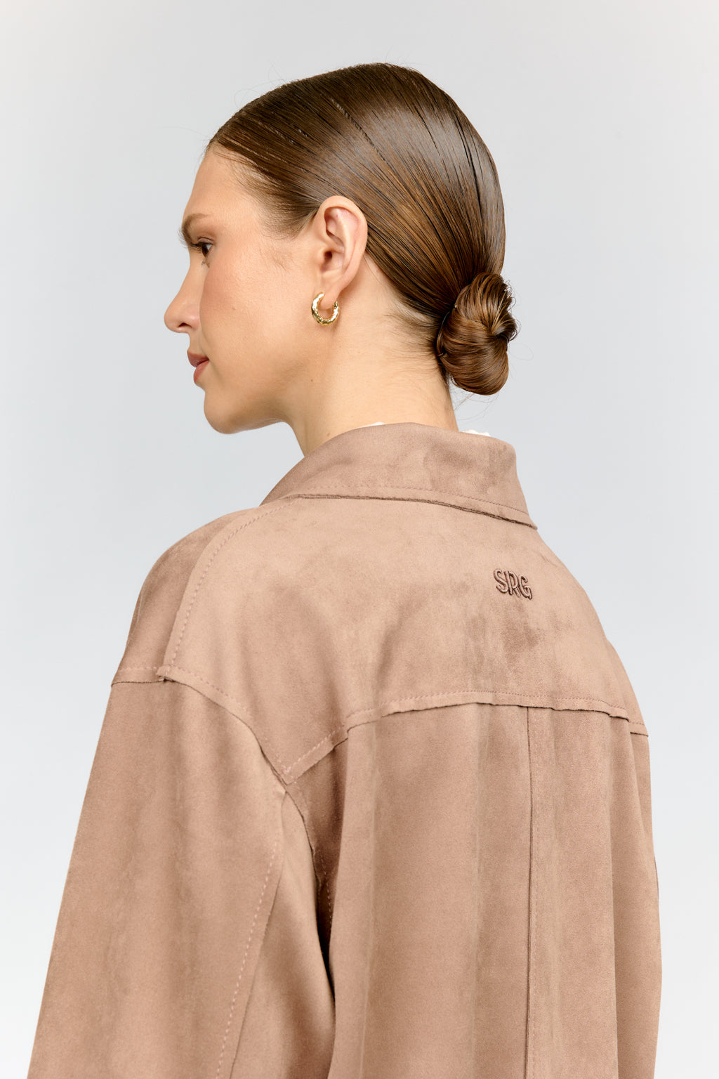 Person wearing a beige jacket with 'SAG' branding on a light gray background