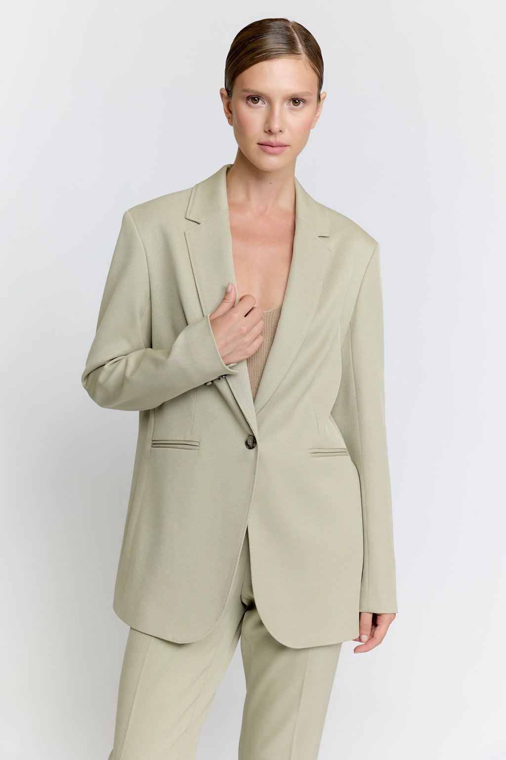 Woman wearing a light green suit against a white background
