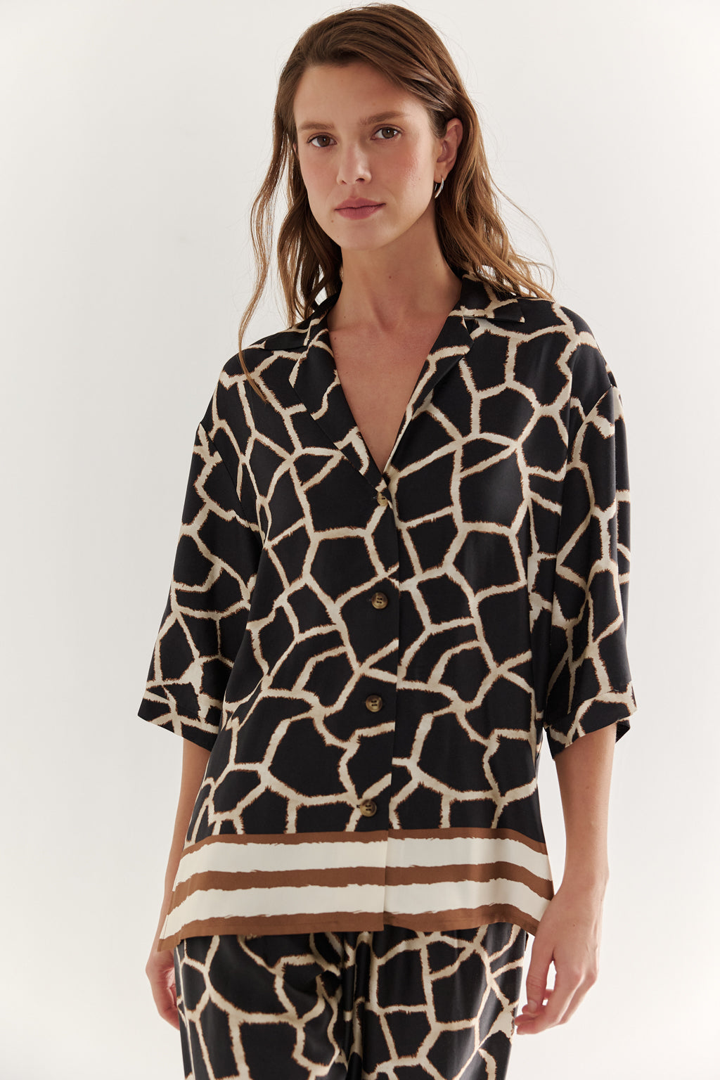 Woman wearing a black and white patterned shirt with a plain background