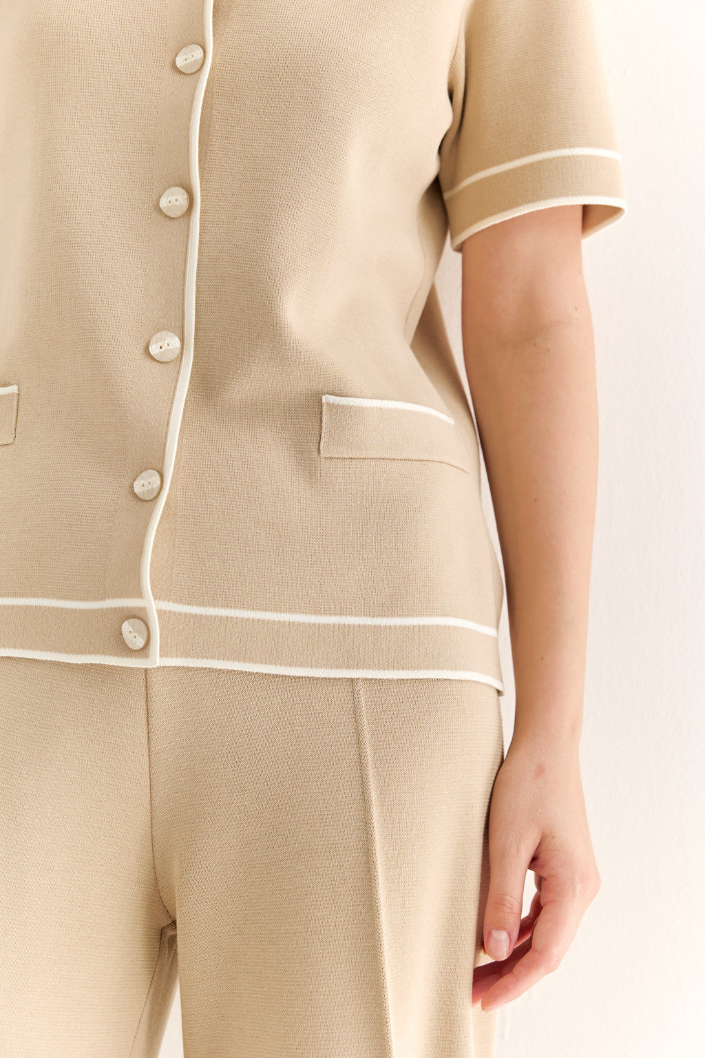 Beige pajama set with white piping on a light background