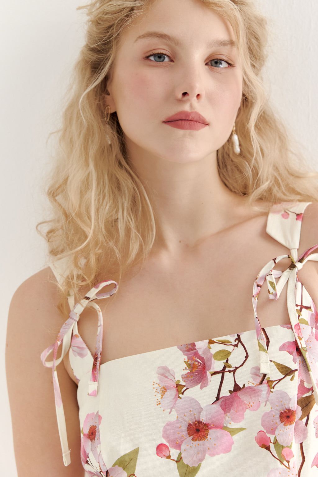Woman wearing a floral dress with pink flowers on a white background