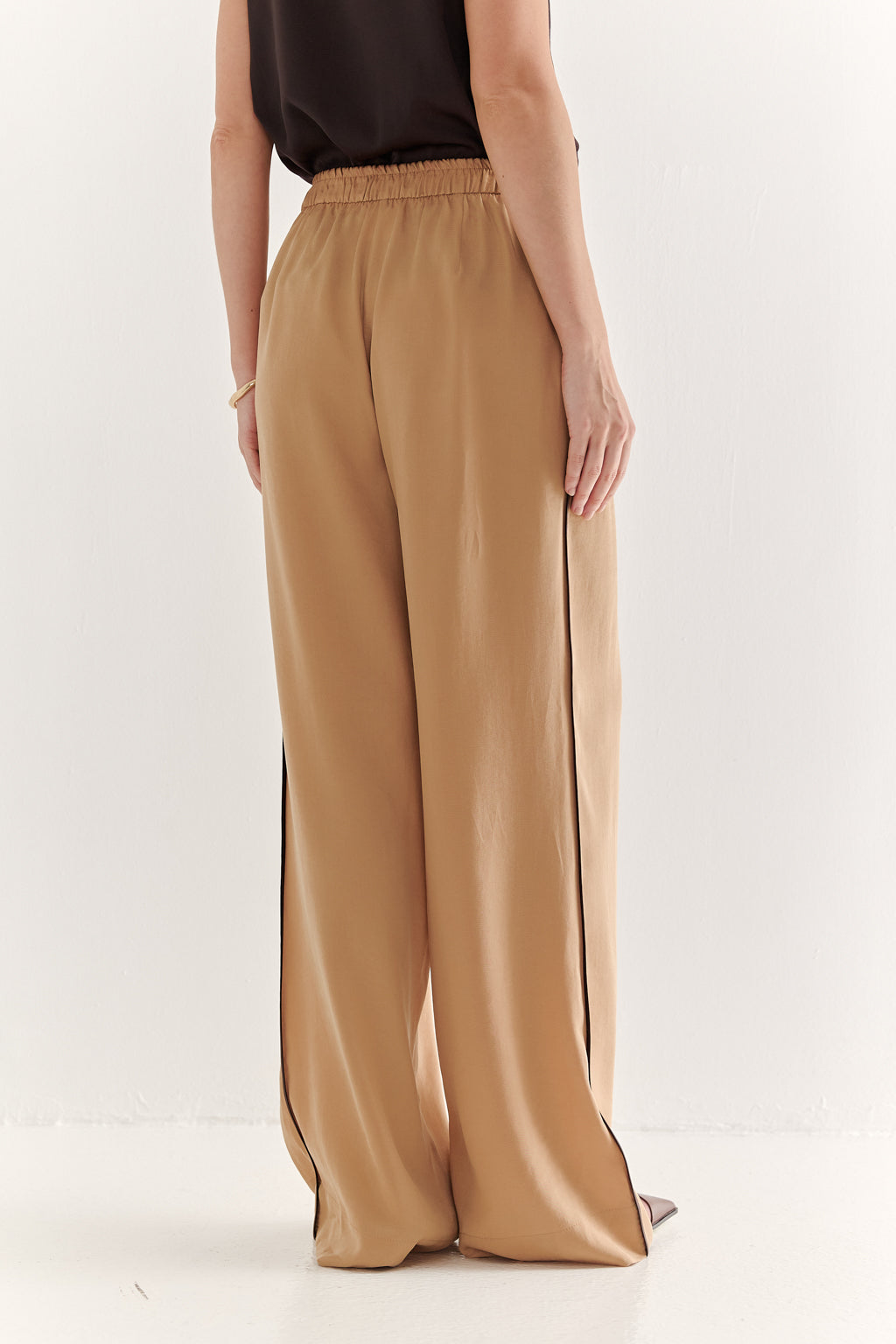 Person wearing tan wide-leg pants on a white background