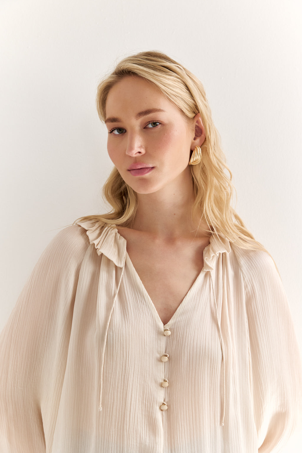 Woman wearing a beige blouse with a plain background