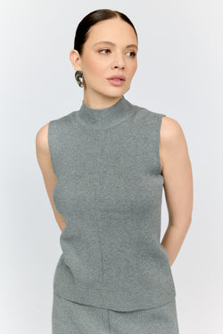 Woman wearing a gray sleeveless top with a plain background