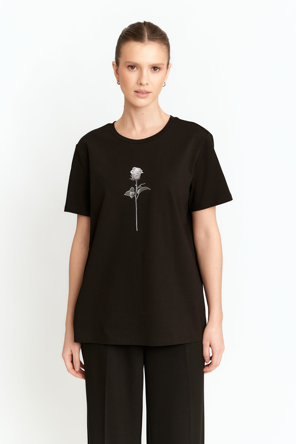 Person wearing a black t-shirt with a white rose design on a white background