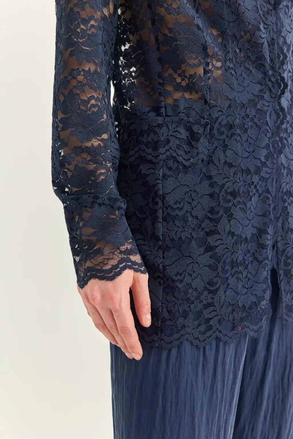 Ayra Store based in New York united states of America Woman wearing AYRA Vinyl Corded Lace Jacket with notched lapel and scalloped hem paired with fluid navy blue trousers