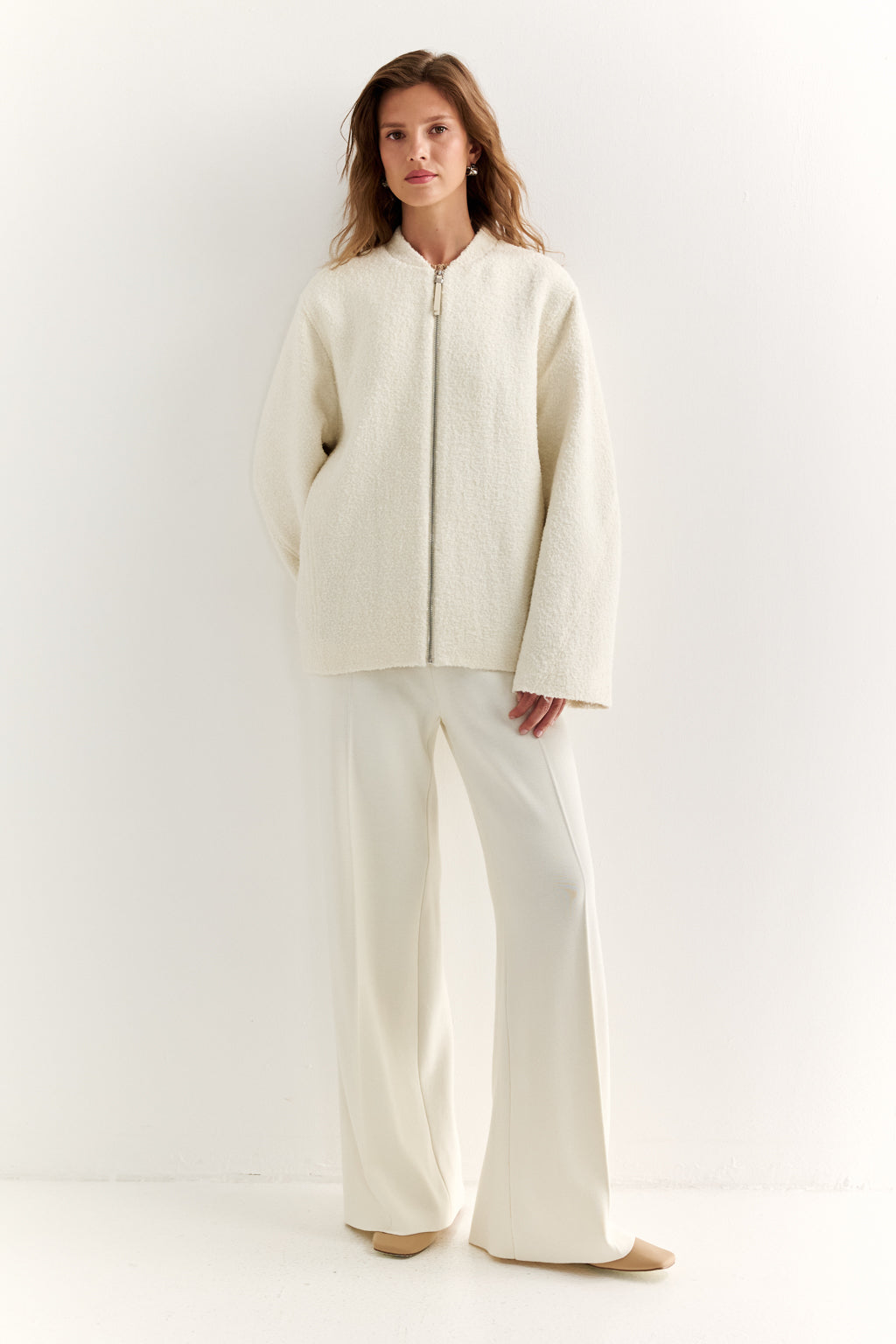 Woman wearing a cream-colored outfit on a white background