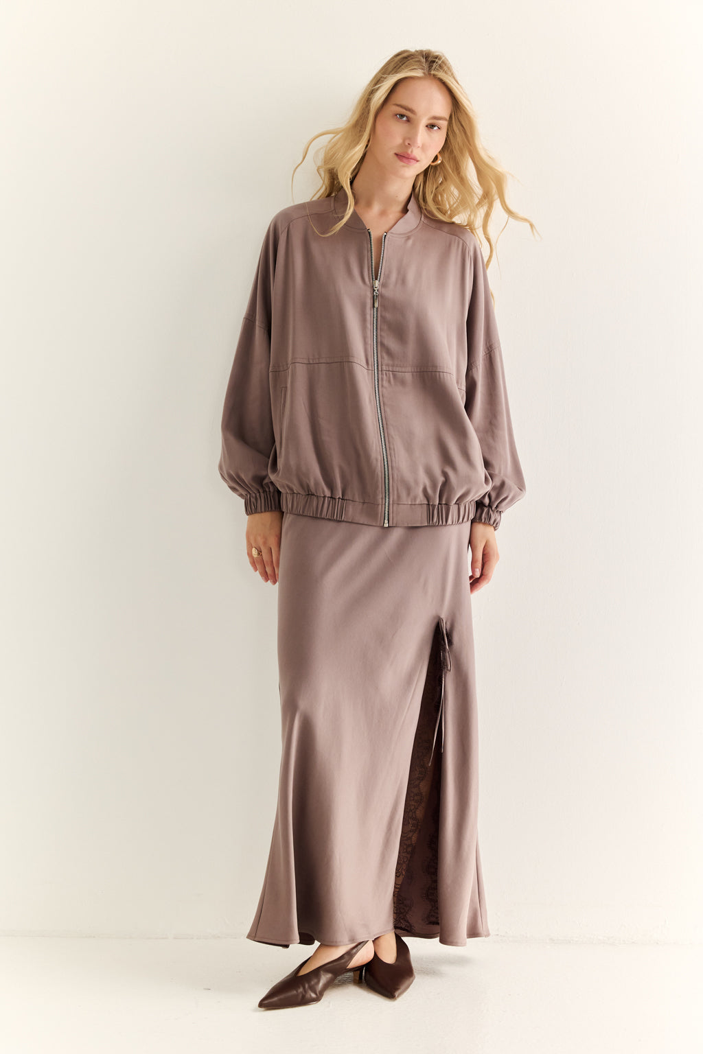 Woman wearing a brown outfit with a jacket and skirt on a white background